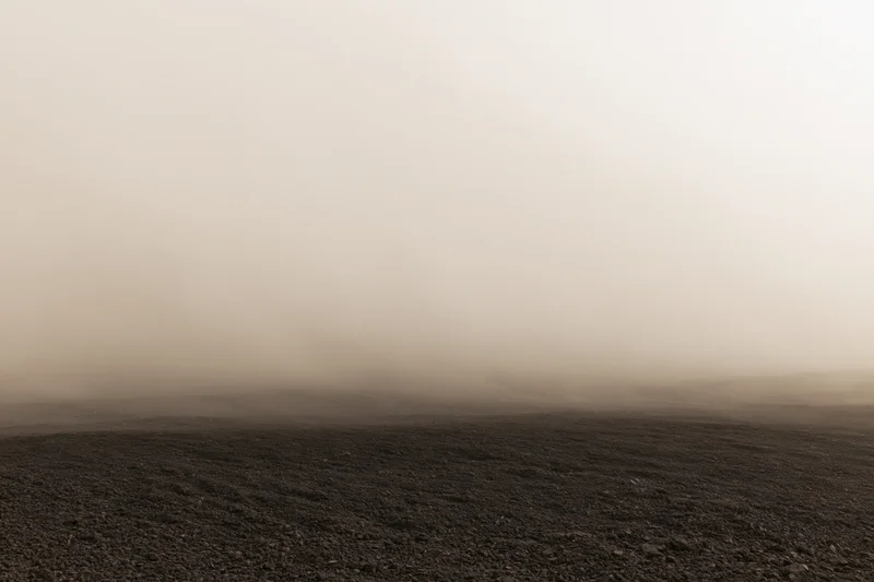 Thick dust cloud rolling low over dark rocky ground