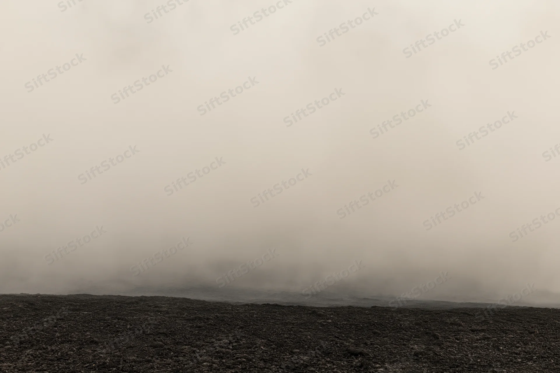 Thick smoke rolling low over dark rocky ground