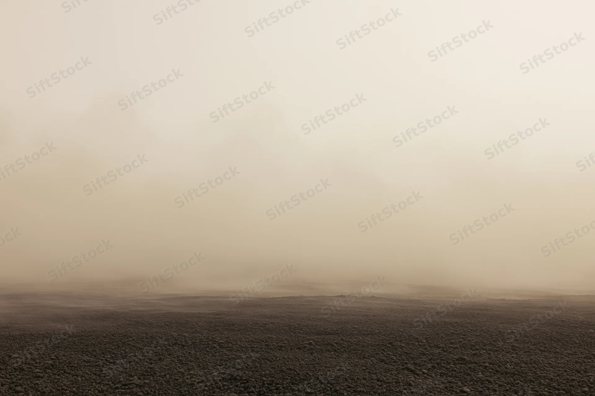 Thick dust cloud rolling low over dark rocky ground
