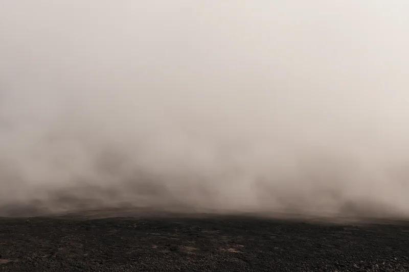 Thick smoke rolling low over dark rocky ground