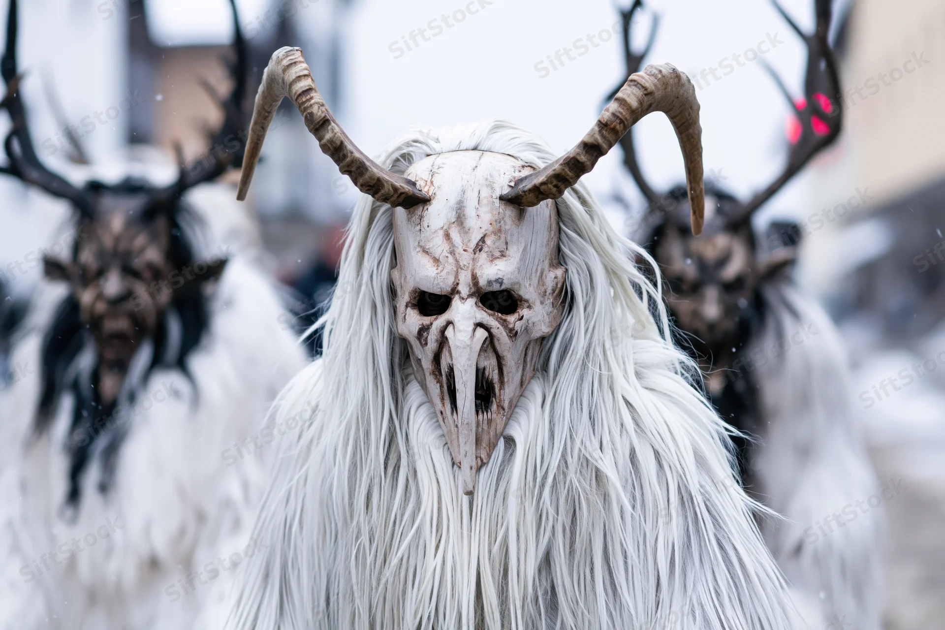 Krampus performer in white fur costume with horned mask during alpine winter festival