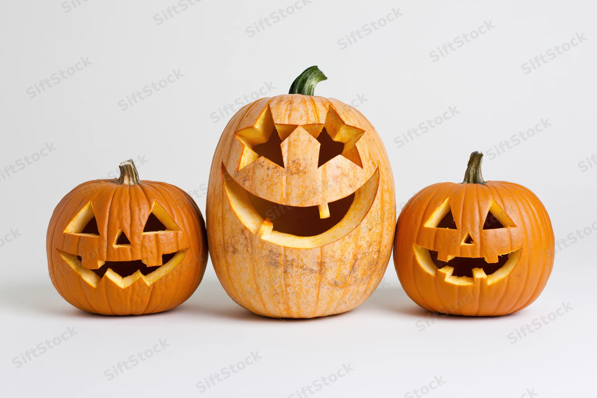 Three carved jack-o-lanterns arranged in a row on a white background