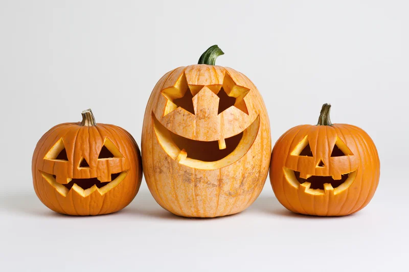 Three carved jack-o-lanterns arranged in a row on a white background