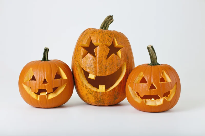 Three carved pumpkins arranged in a row on a white surface