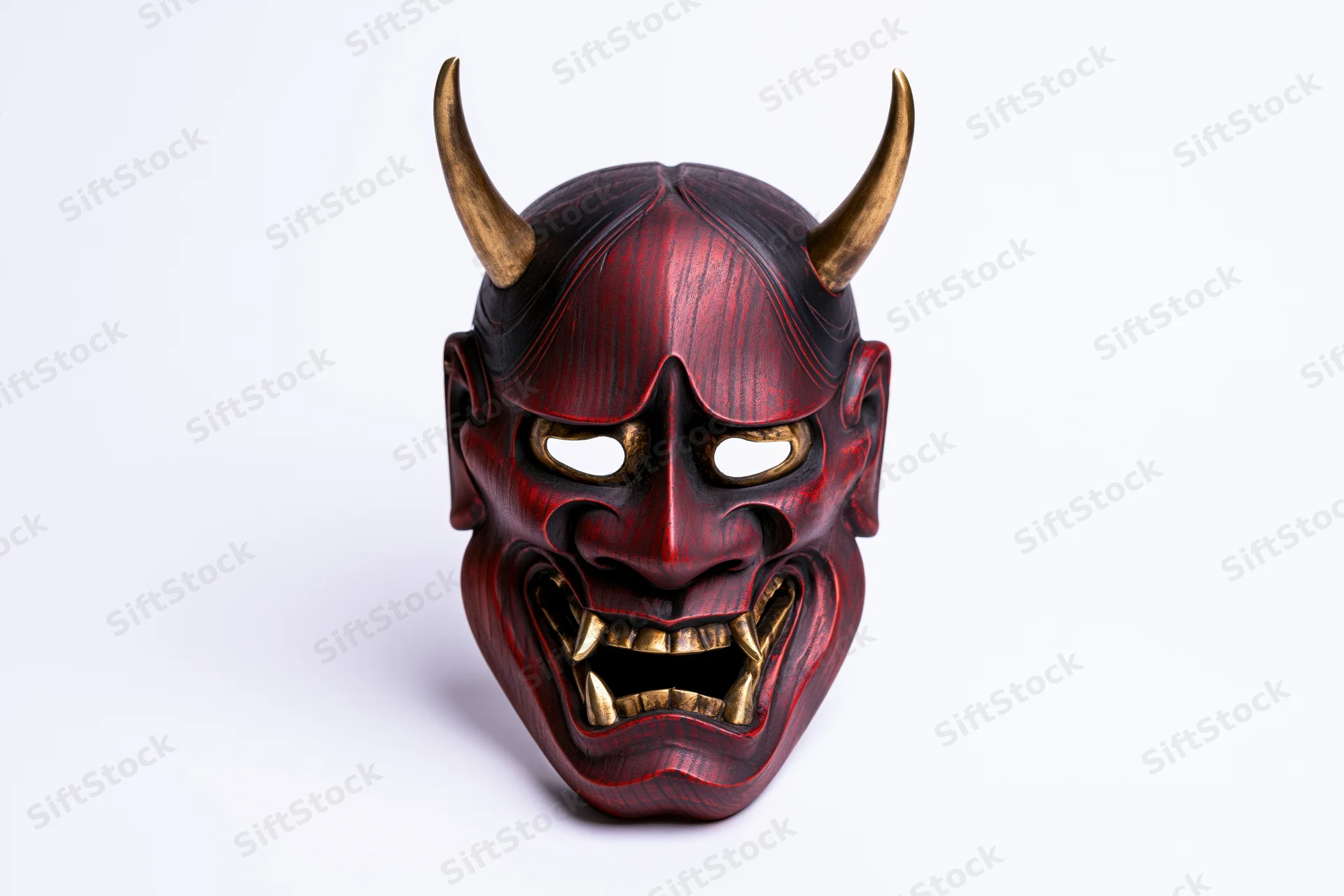 Traditional japanese hannya noh theater mask with red lacquered wood and gold horns displayed face-on against white background