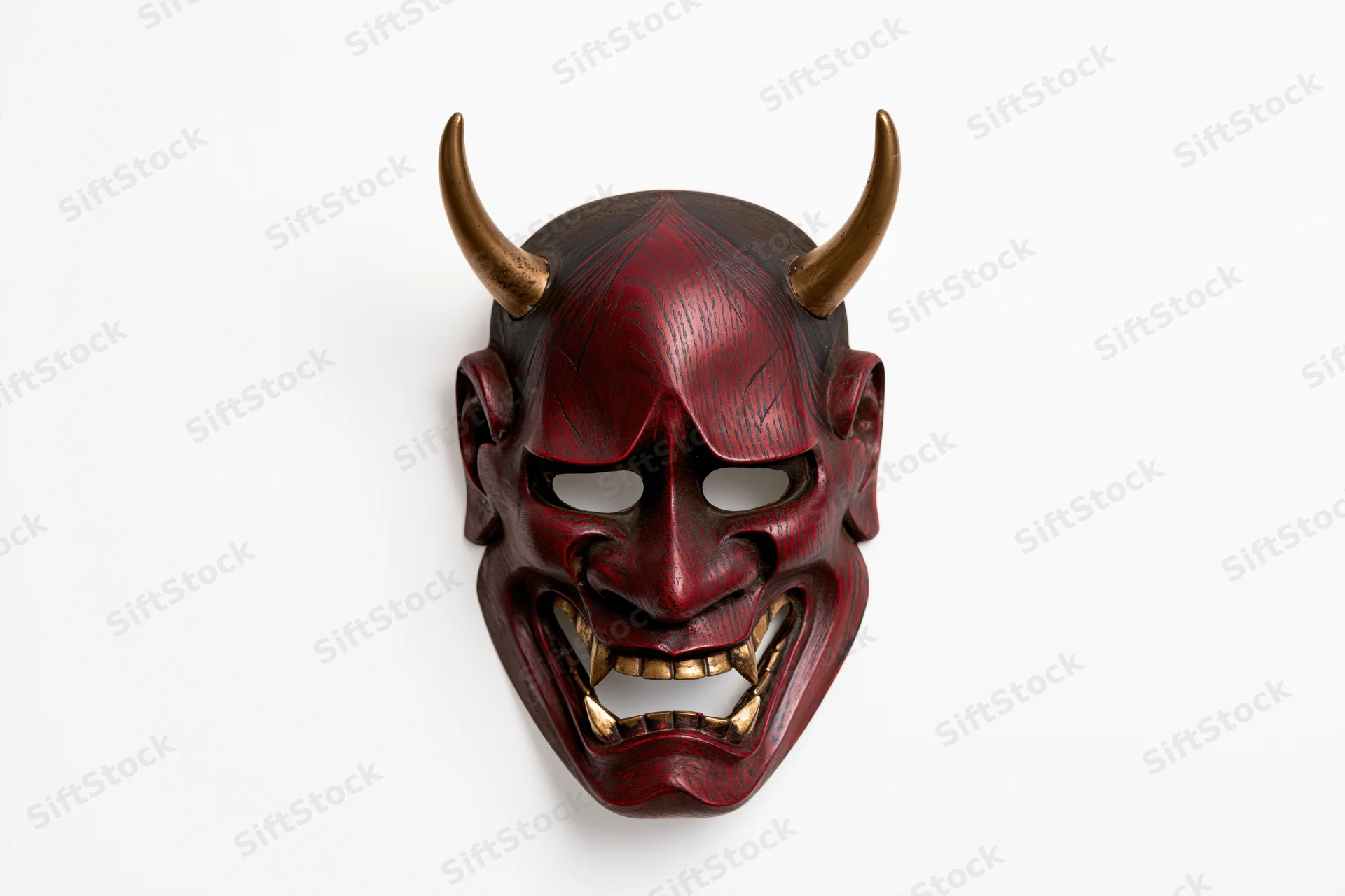 Traditional japanese hannya noh theater mask with red painted face and golden horns displayed on white background