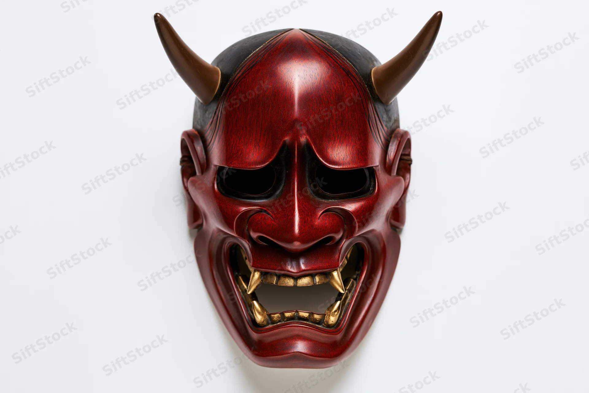 Red horned hannya noh theater mask with open mouth and gold fangs on white background