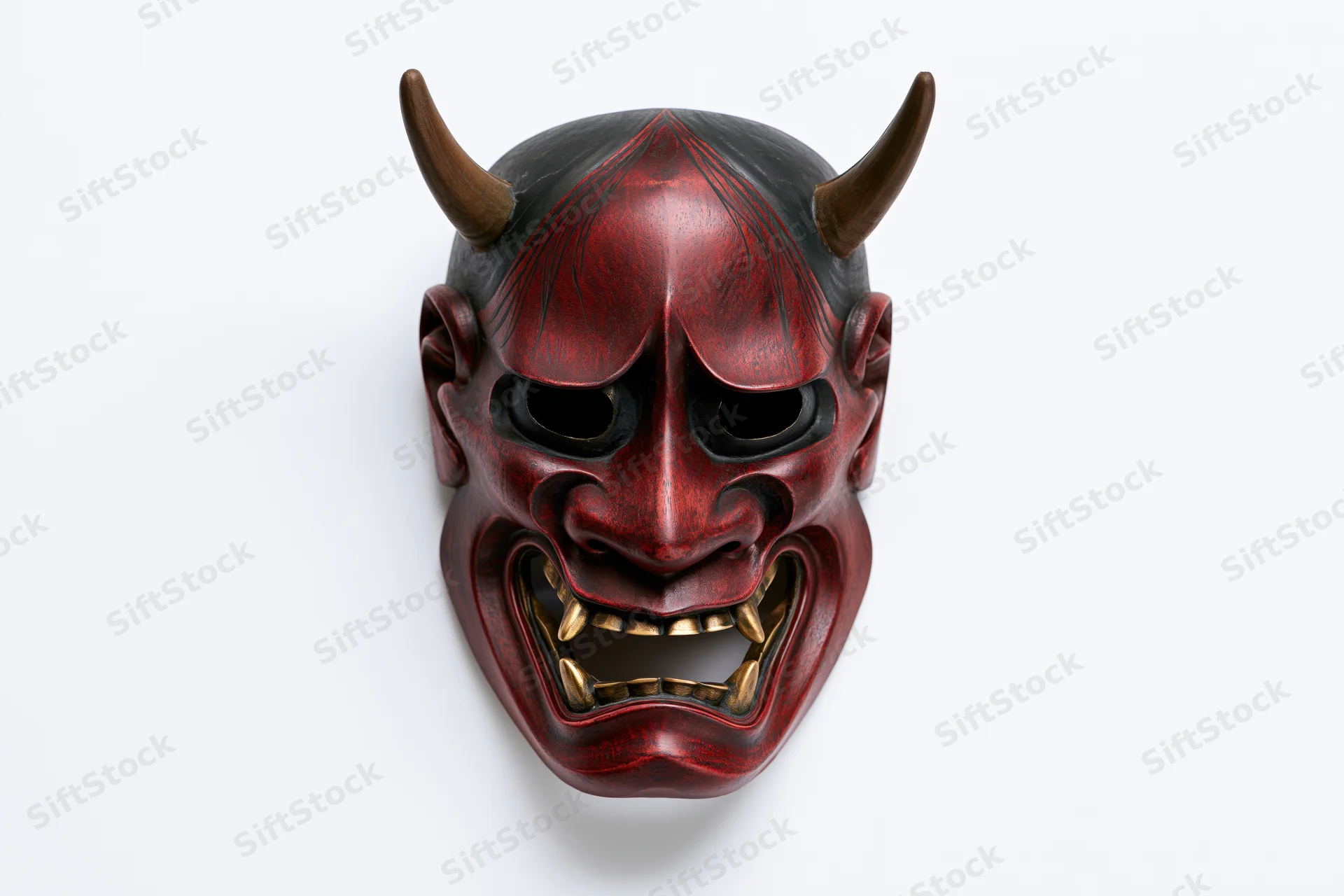 Traditional japanese hannya noh theater mask with red face black horns and gold teeth on white background