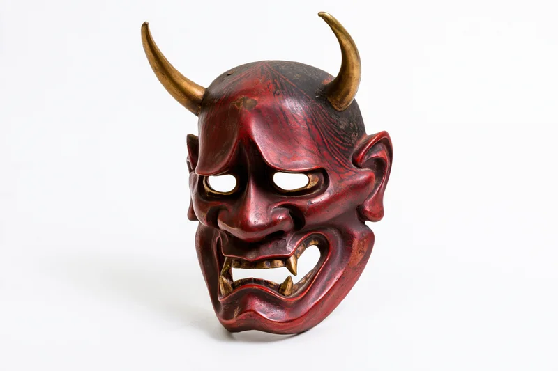 Traditional japanese hannya noh theater mask with red lacquered surface and golden horns isolated on white background