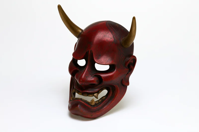 Traditional japanese hannya noh theater mask with horns and fanged expression on white background