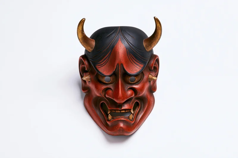 Traditional japanese hannya demon mask with red face and black horns displayed face-forward on white background