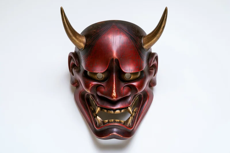 Traditional japanese hannya demon mask with red lacquer and gold horns displayed face-forward on white background