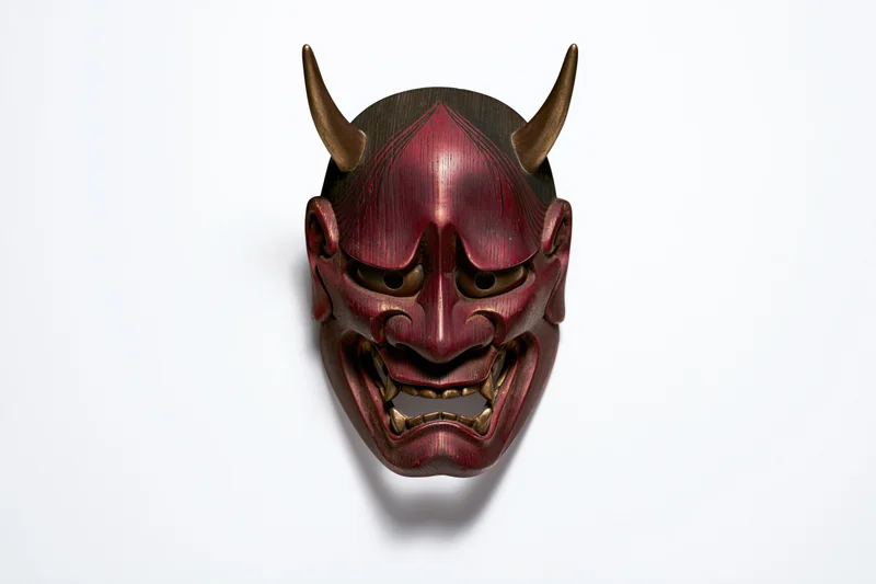 Traditional japanese hannya demon mask with horns and fanged expression displayed face-forward on white background