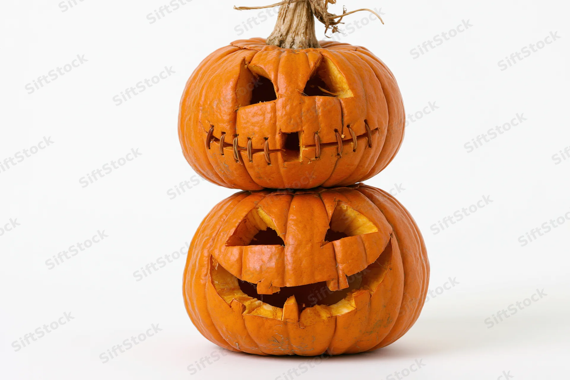 Two carved jack-o-lanterns stacked vertically on a white background