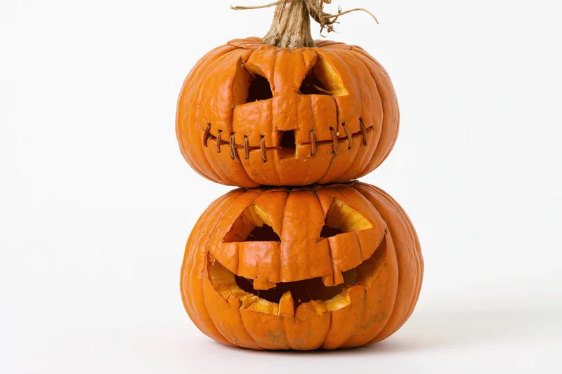 Two carved jack-o-lanterns stacked vertically on a white background
