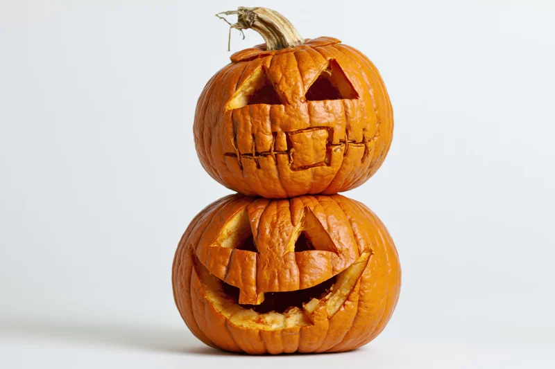 Two carved jack-o-lanterns stacked vertically on a white background