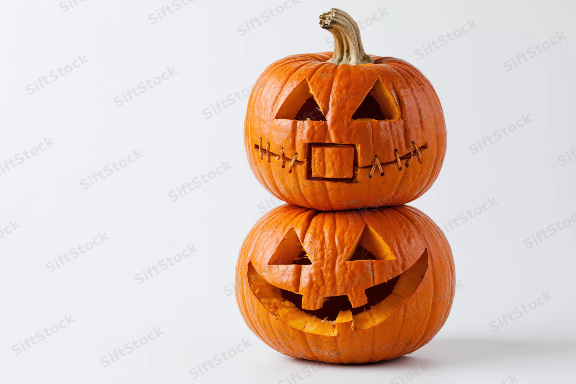 Two carved jack-o-lanterns stacked vertically on a white background