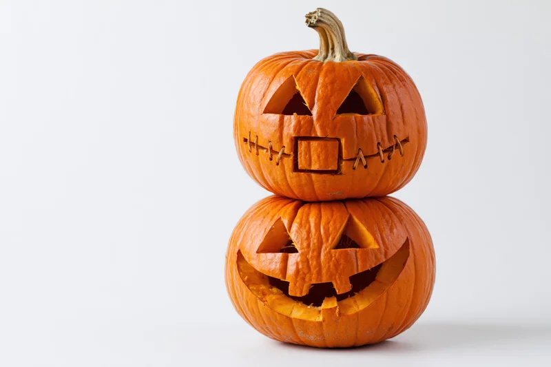 Two carved jack-o-lanterns stacked vertically on a white background