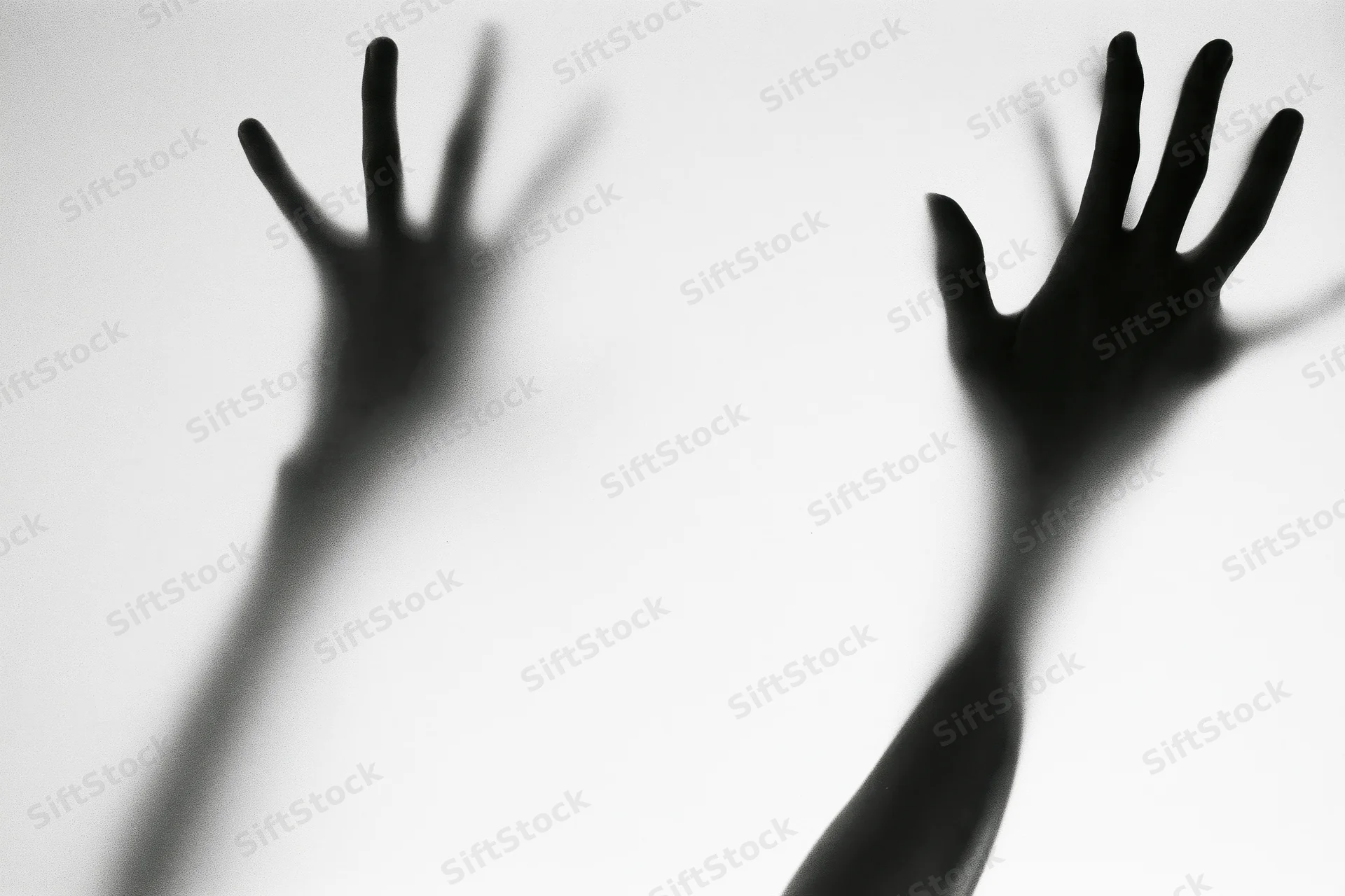 Silhouetted hands pressing against frosted glass in a darkened space