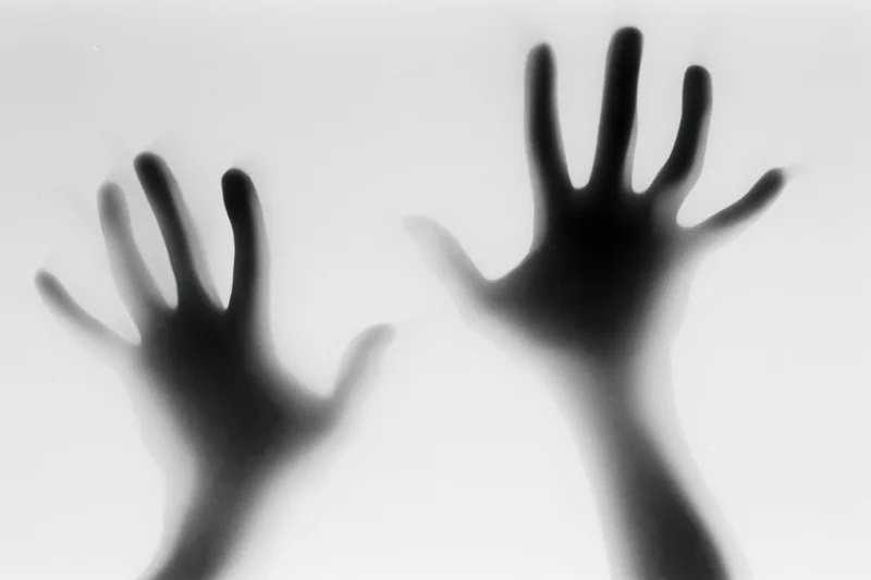 Two hands pressing against a fogged glass surface