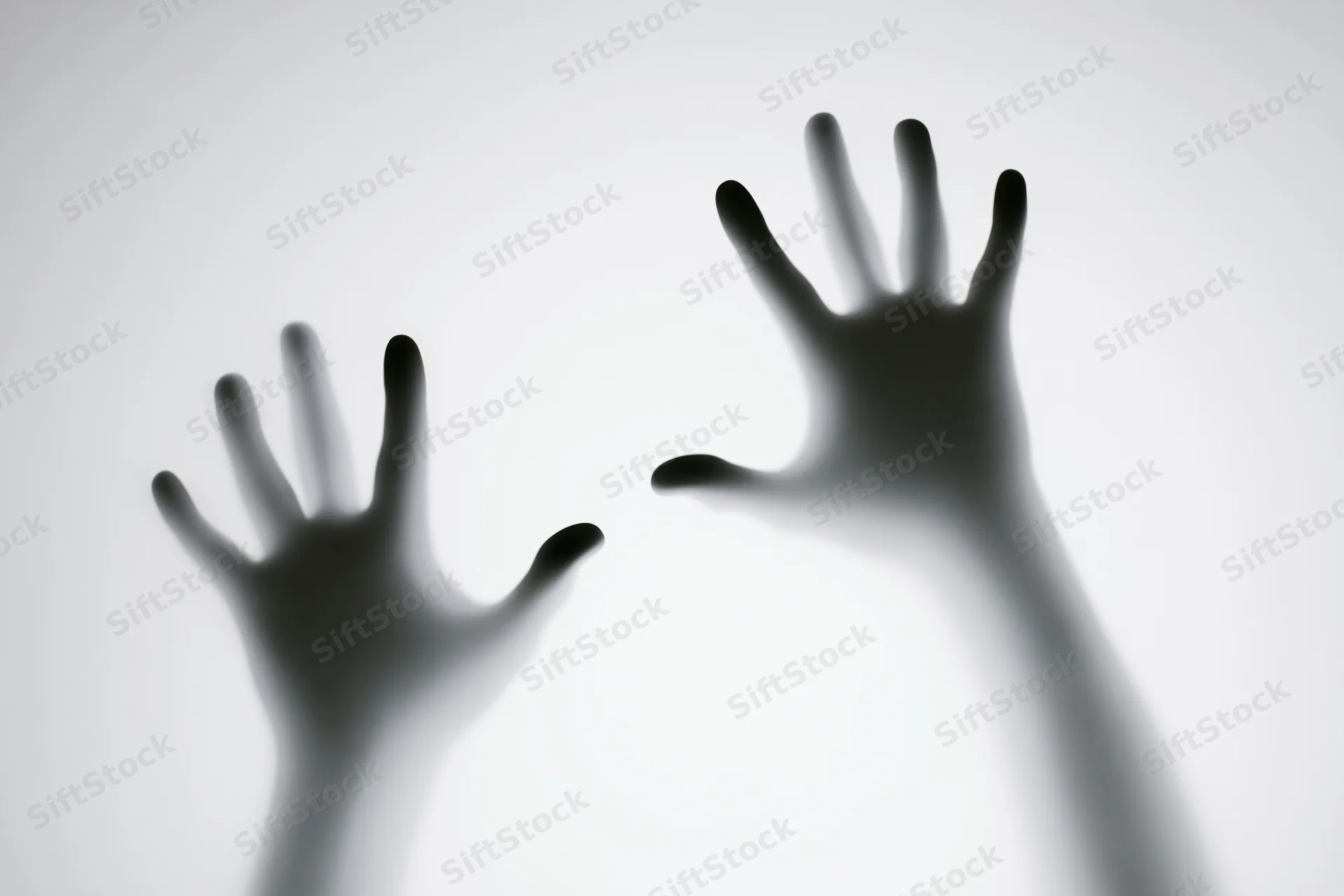 Two hands pressed against frosted glass in silhouette