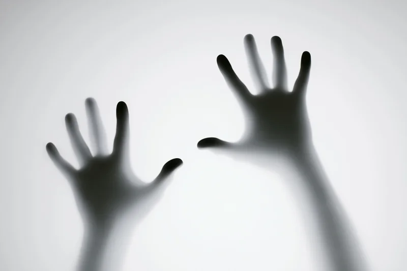 Two hands pressed against frosted glass in silhouette