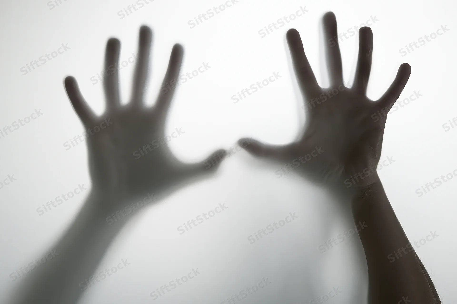 Two hands pressed against frosted glass with fingers spread, one hand in focus and the other blurred, creating a shadowy silhouette effect