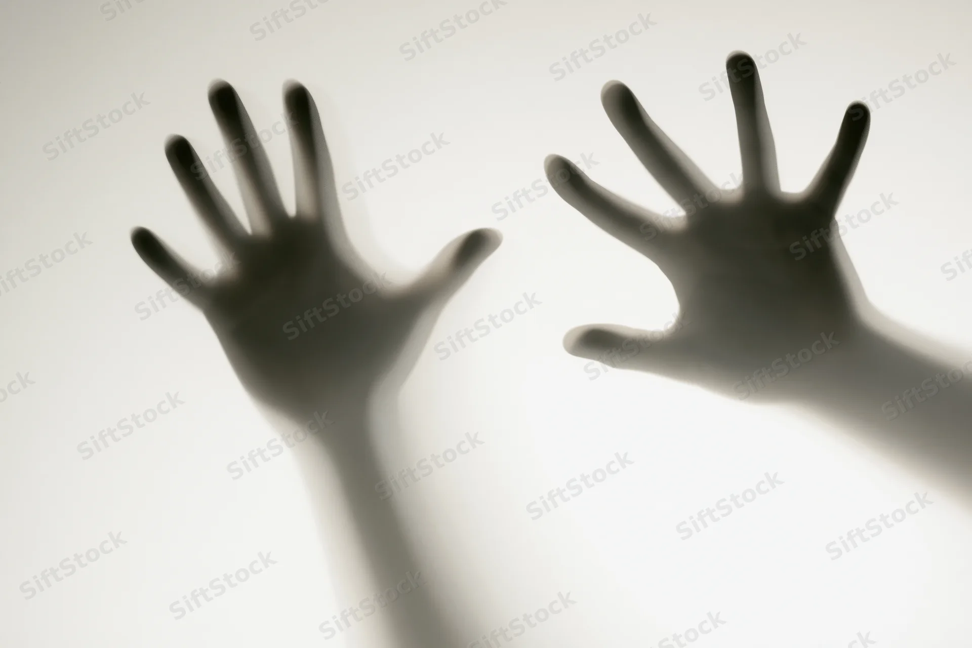 Two hands pressed against frosted glass in silhouette
