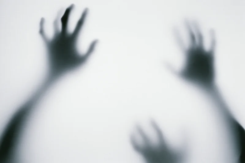 Blurred hands pressing against frosted glass surface