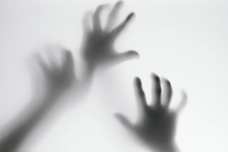 Blurred hands pressing against frosted glass surface
