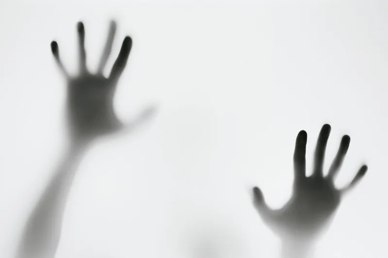 Two hands pressing against a frosted glass surface
