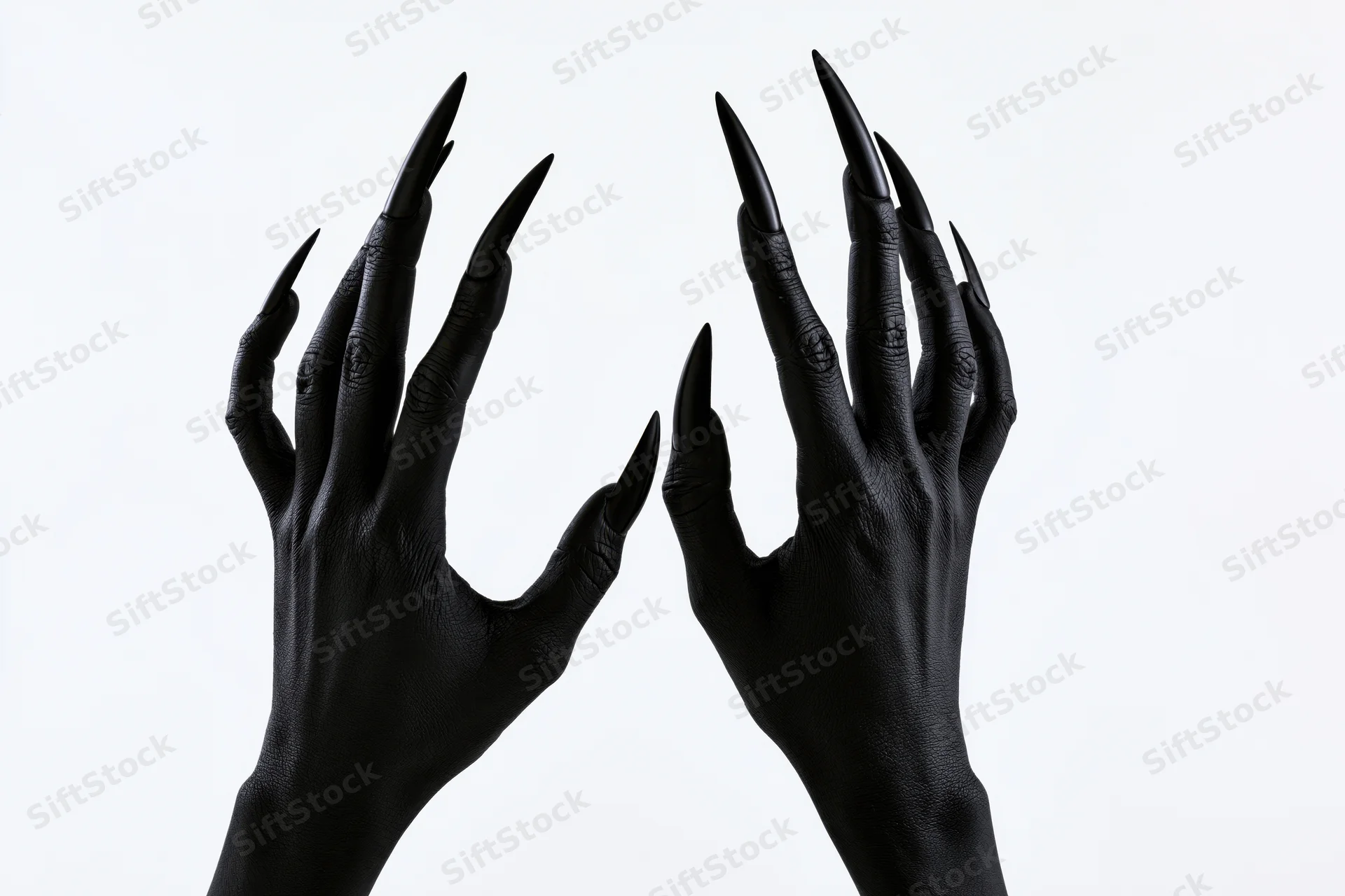 Two matte black painted human hands with long sharp black nails raised against white background