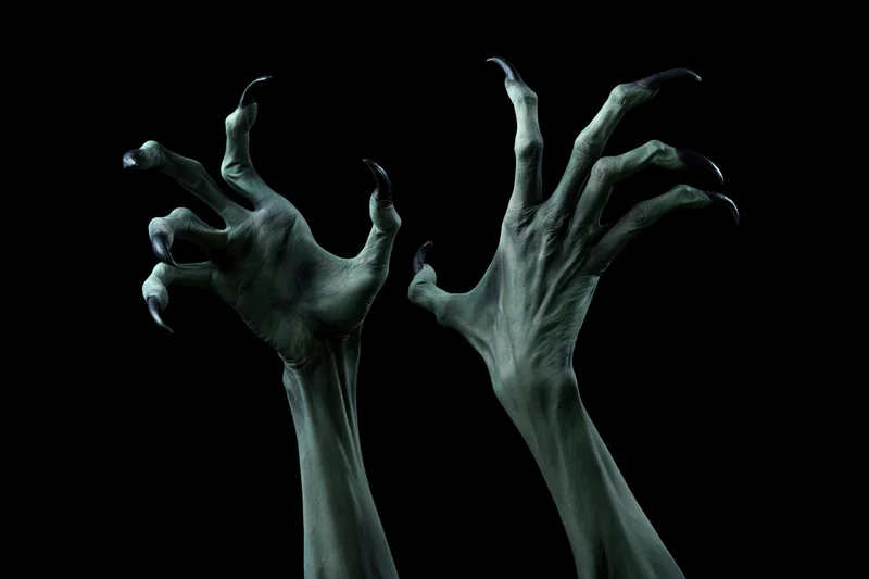 Two pale green monster hands with sharp claws reaching upward against black background