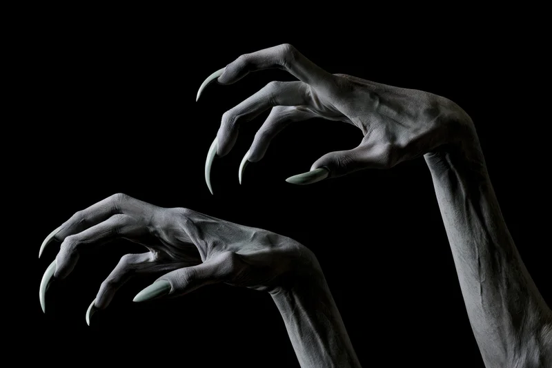 Pale grey creature hands with long curved claws reaching against black background