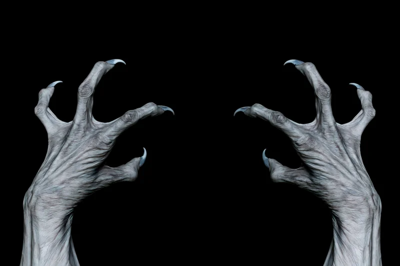 Two pale grey monster hands with long sharp claws reaching upward against black background