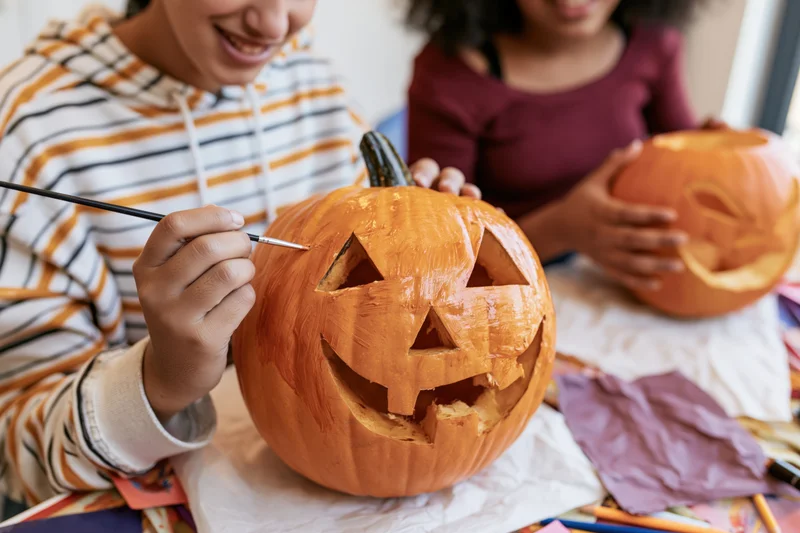 Children carving and painting pumpkins at a table for halloween