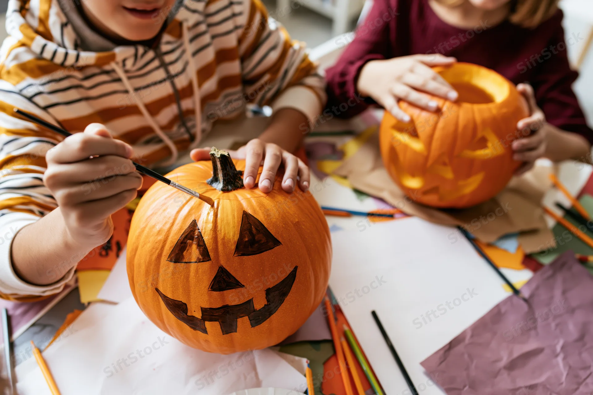 Children painting and carving pumpkins at a craft table for halloween