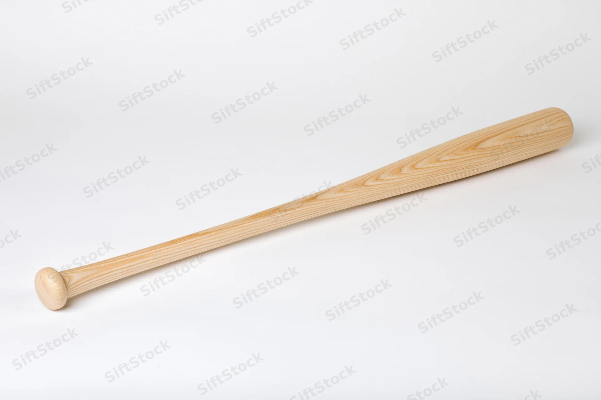 Unfinished wooden baseball bat lying diagonally on white surface