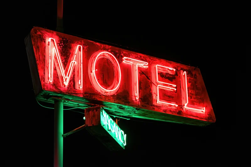 Weathered neon motel sign glowing red at night with green vacancy light below