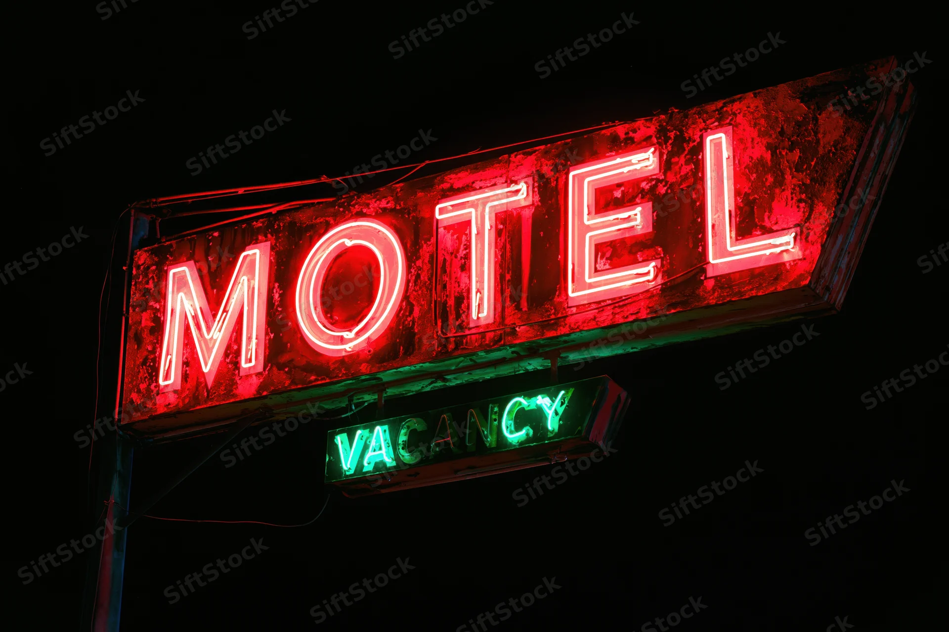 Weathered neon motel sign glowing red and green at night against dark sky