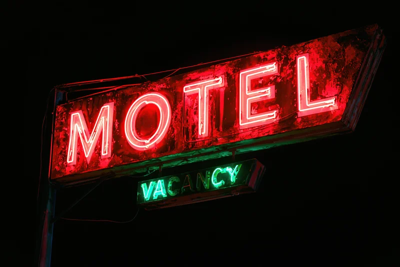 Weathered neon motel sign glowing red and green at night against dark sky