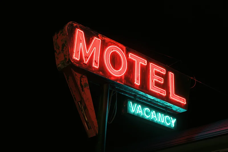 Weathered neon motel sign glowing red and green at night against dark sky