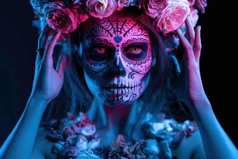 Woman with sugar skull face paint and floral crown in neon lighting
