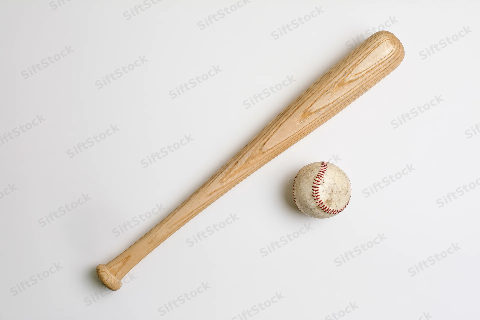 Wooden baseball bat and worn leather baseball arranged diagonally on white background