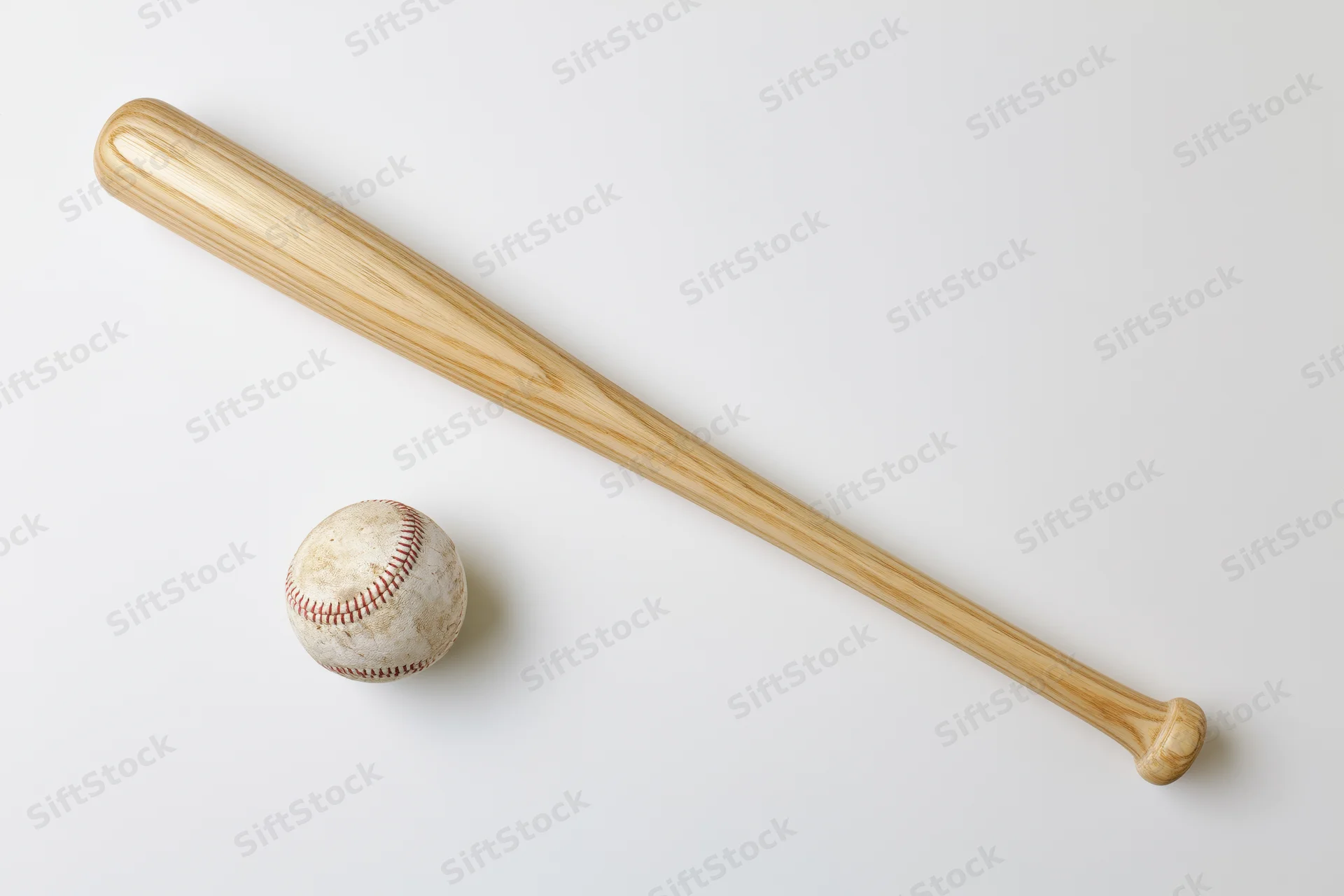 Wooden baseball bat and worn leather baseball arranged diagonally on white background