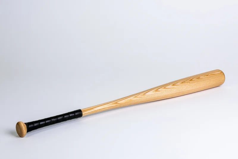 Wooden baseball bat lying diagonally on plain white surface