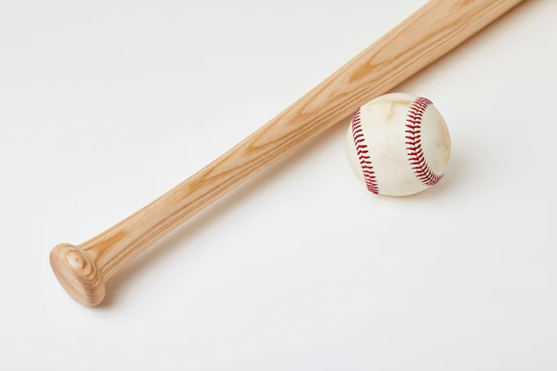 Wooden baseball bat and white leather baseball resting diagonally on white background