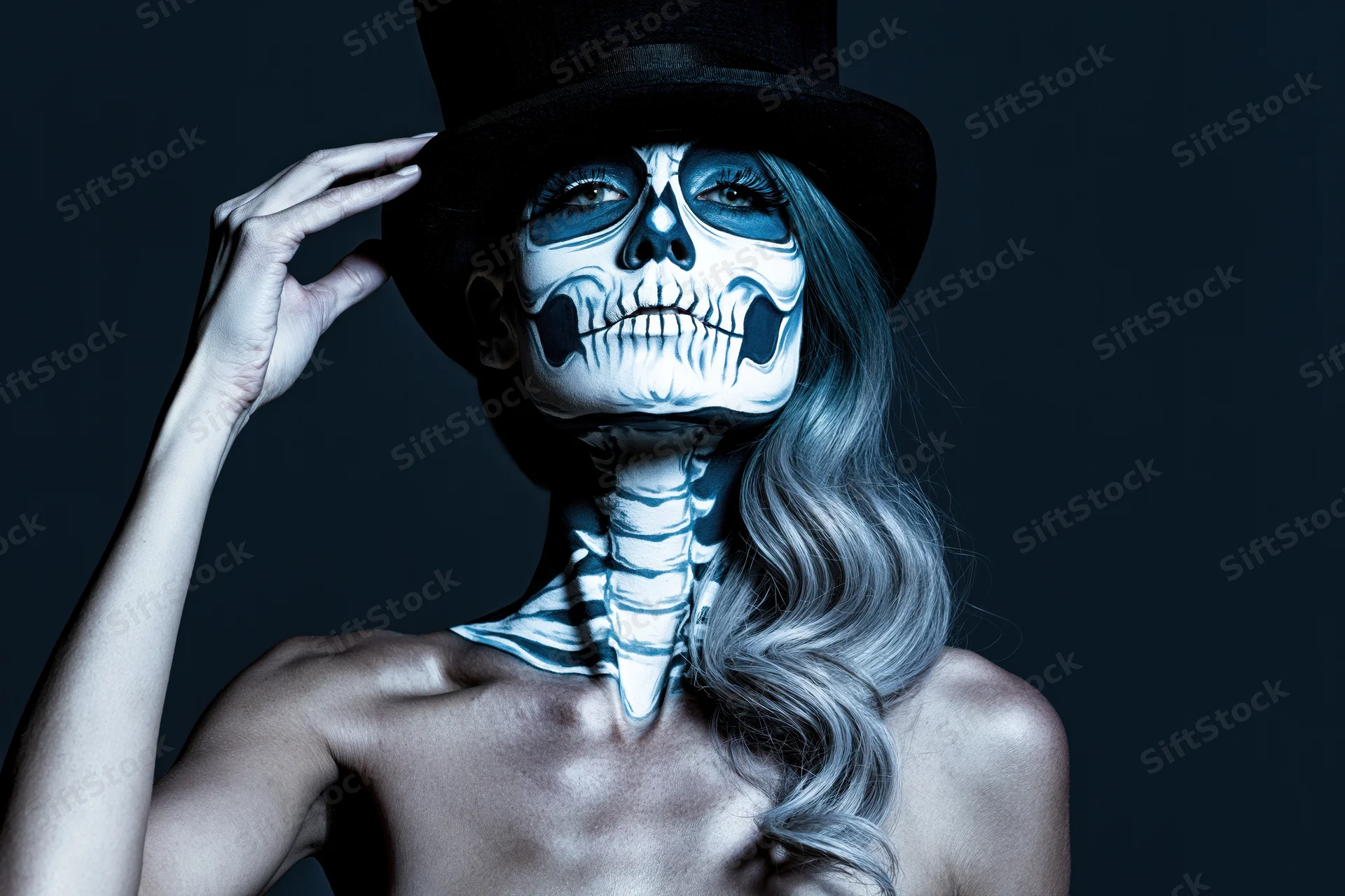 Woman with skeleton face paint and top hat posing in studio