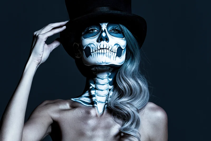 Woman with skeleton face paint and top hat posing in studio