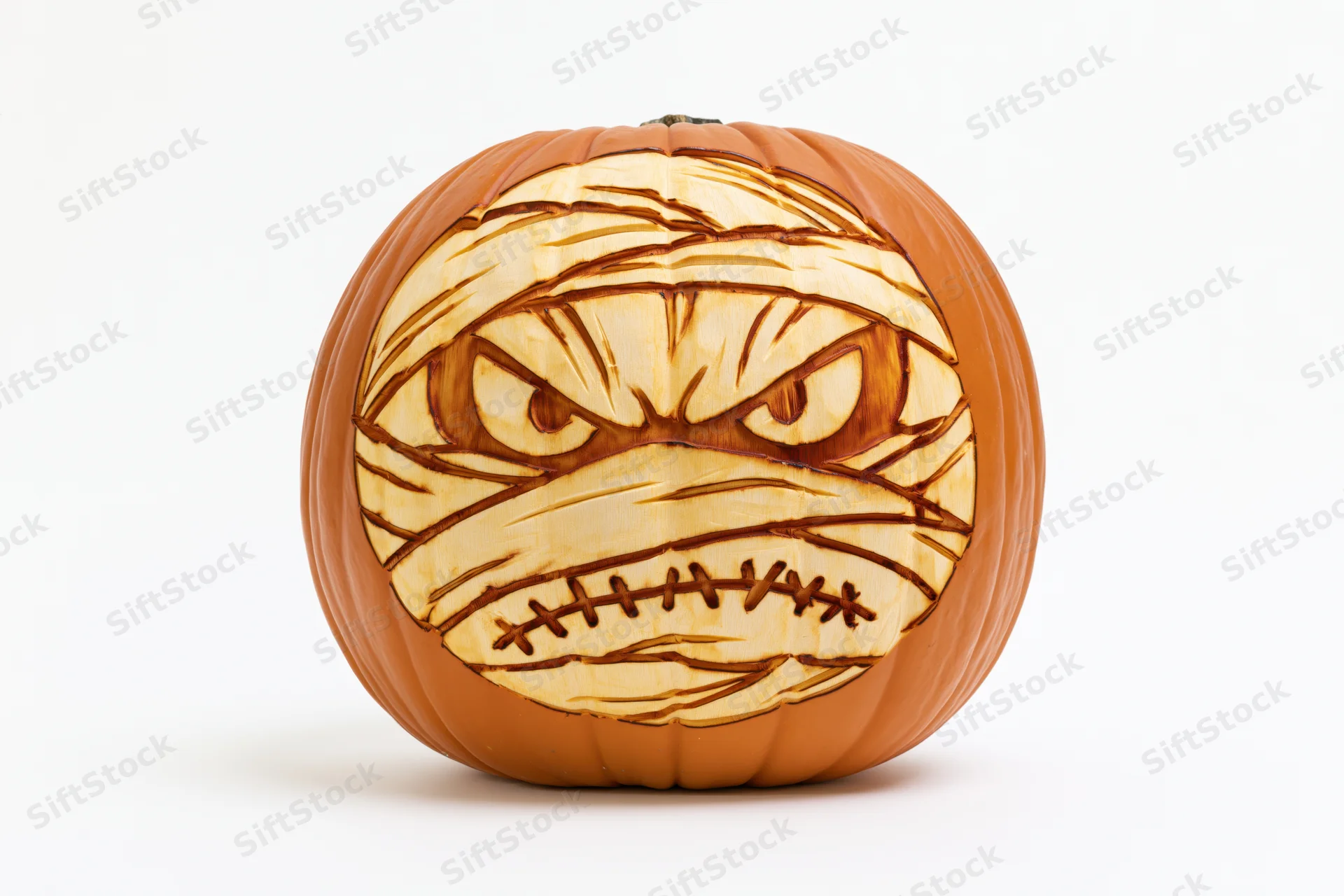 Carved pumpkin with mummy face design on white background